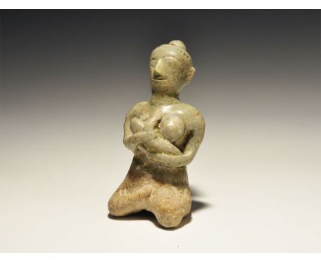 14th-16th century AD. A grey-glazed ceramic figurine of a nursing mother sitting with legs crossed to the side, hair drawn up