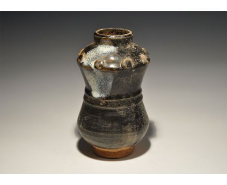 An undated archaistic black-glazed ceramic waisted jar with gussetted collar, low rim, band of applied pellets to the shoulde