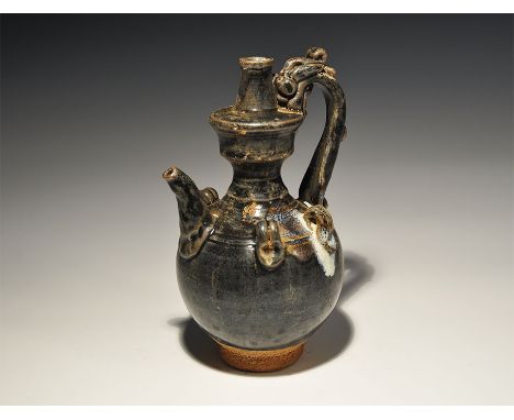 An undated archaistic black-glazed ceramic pitcher with bulbous body, four lateral loops to the shoulder, tall tiered neck wi