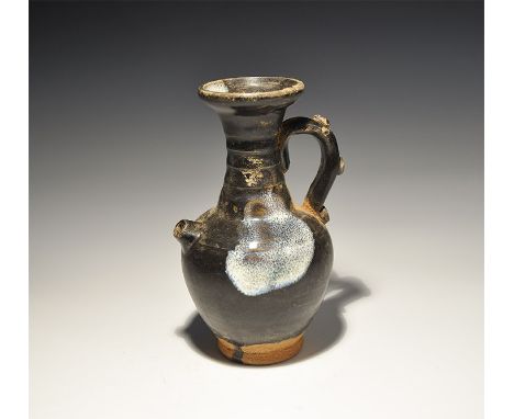 An undated archaistic black-glazed ceramic pitcher with bulbous body, tubular waisted neck, flared mouth, scrolled handle wit