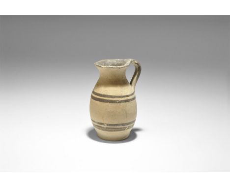 4th century BC. A ceramic buffware jug with ovoid body, flared rim and strap handle, concentric black lines to the shoulder a