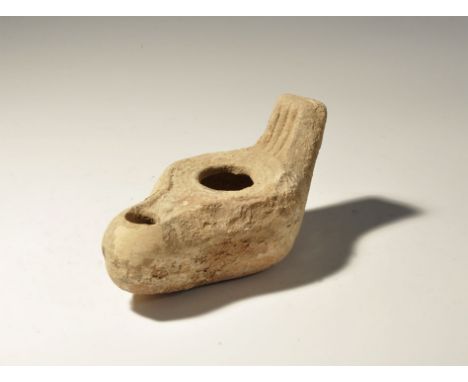 6th-9th century AD. A ceramic slipper-shaped lamp with concentric ribbing to the discus, long nozzle, ribbed lug handle to th