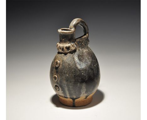 An undated archaistic black-glazed ceramic vessel with bulbous body, loop handle and short spout with pinched collar, three a