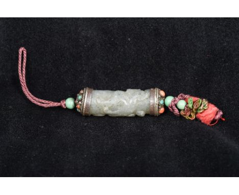 A Tibetan unmarked white metal mounted carved jade pendantOf cylindrical form, carved in the round with a mythical beast, set