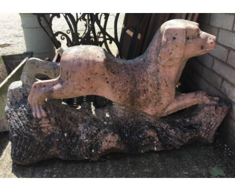 A Chinese carved pink granite model of a dogModelled with all four legs stretched out, on a naturalistic rocky base.  105 cm 