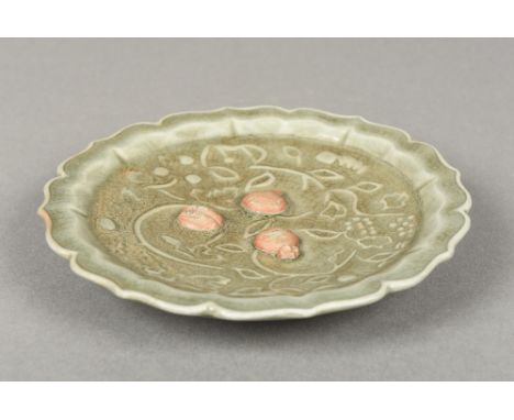 A Chinese Ming Dynasty porcelain celadon glazed dishWorked with scrolling vines and unglazed fruits within a shaped rim, old 