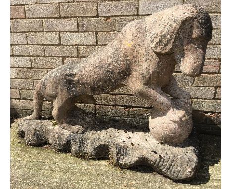 A Chinese carved pink granite model of a dog Modelled standing with his front paws on a ball, on a naturalistic base.  105 cm