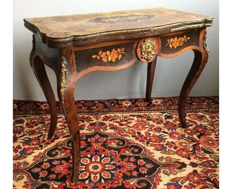 A 19th century marquetry inlaid walnut card tableThe shaped hinged revolving top centred with a floral marquetry panel amongs