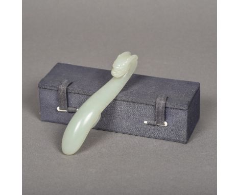 A Chinese carved celadon jade belt hookOf typical form, with dragon mask terminal, in fitted box.  12.5 cm long.    CONDITION
