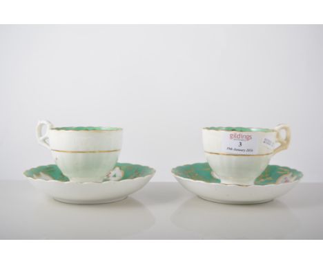 Pair of Victorian cups and saucers, green and gilt borders, painted with floral sprays, the saucer diameter 15cms.
