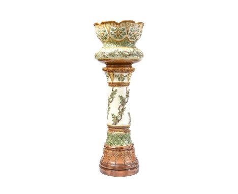 A Burmantofts Faience Pottery Jardinière and Stand, decorated with repeating patterns and leaves, in tones of green, yellow a