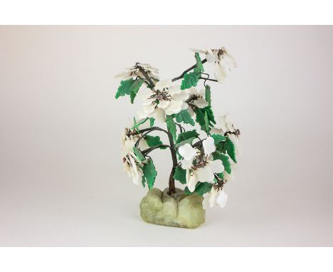 A Chinese hardstone miniature tree with green and white hardstone leaves and petals (some detached) on jade green rock base, 