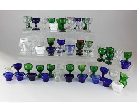 A collection of various glass and ceramic eye baths including some in blue glass marked Optrex Safeguards Sight