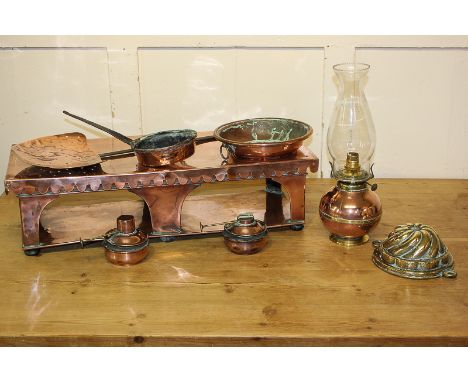 A copper warming plate with burners, a converted oil lamp, a brass jelly mould, a chestnut roasting pan, a strainer and a pan