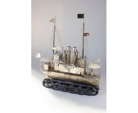A white metal model of a Chinese steamboat with passenger decks and crowsnest, on carved hardwood stand in the form of waves,