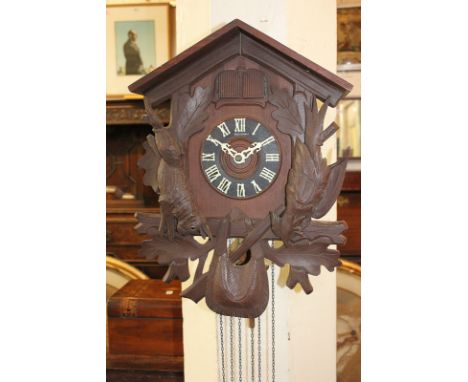 A German Black Forest style cuckoo clock with carved detail of a hare and pheasant, with three weights and pendulum