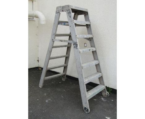 A vintage folding six rung industrial step ladder on large casters / wheels, 180cm high, 53cm wide.