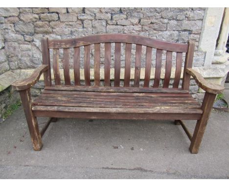 An Alexander Rose stained and weathered teak three seat garden bench with curved slatted seat and back beneath an arched rail