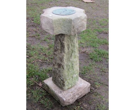 A circular weathered sundial set on a rough hewn three sectional base, 65 cm high, together with further loose dial