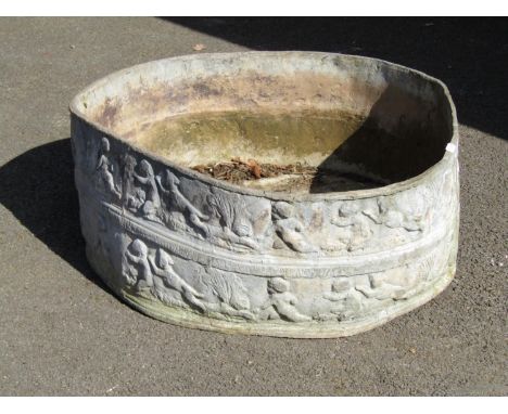 An old weathered squat circular lead planter with repeating cherub, hound and further classical detail, 23cm high x 60cm diam
