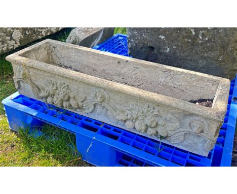 A weathered cast composition stone rectangular flower trough with repeating lions mask and fruiting vine detail, raised on a 