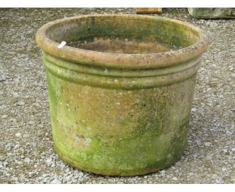 A weathered terracotta planter of simple circular tapered form with rolled rim, 36 cm high x 50 cm diameter approximately