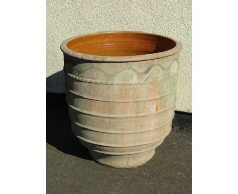 A large weathered terracotta planter with ribbed and combed exterior and glazed interior, 67cm high, 65cm diameter