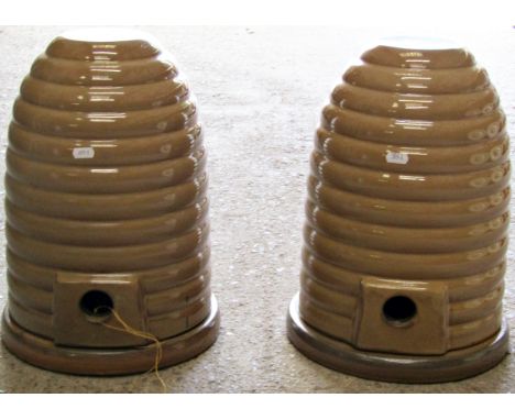 A pair of decorative glazed ceramic beehives / skeps, of traditional stepped arched form with central entrances, raised on ci