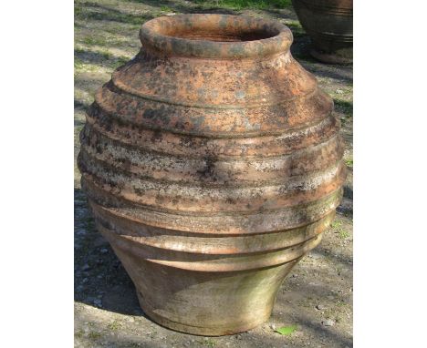 A large weathered Mediterranean terracotta globular shaped olive jar with ring banded detail, 71cm high