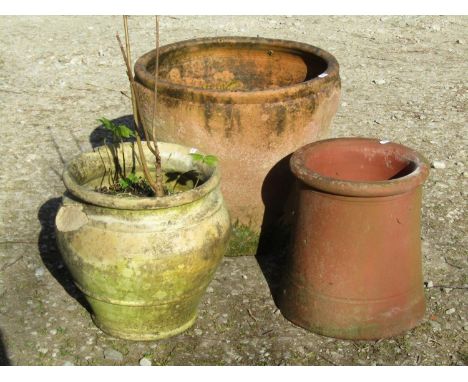 A weathered terracotta planter of circular tapered form, 41cm high x 45cm diameter, a further buff example and a squat chimne