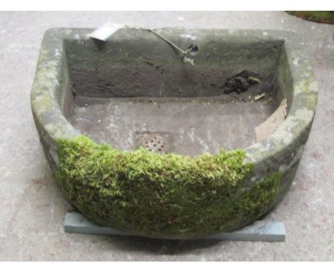 A weathered natural stone trough / plater of D-end / demi-lune form, with pierced drainage bung, 24cm high, 52 x 64cm.