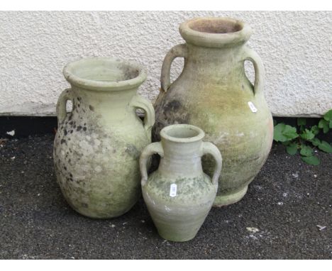 Three small varying twin-handled weathered twin handled olive / amphora jars, the largest 39cm high (3)