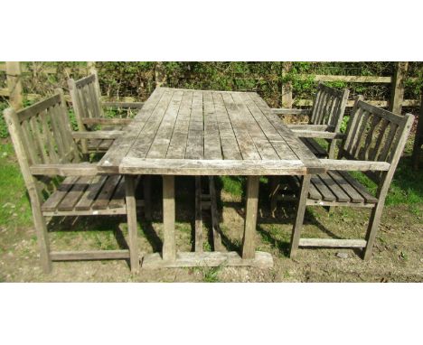 A weathered (silvered) teak garden table with overhanging rectangular slatted top raised on square cut and sledge supports un
