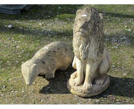 A weathered cast composition stone garden ornament in the form of a seated lion, 54 cm high, together with three further gard