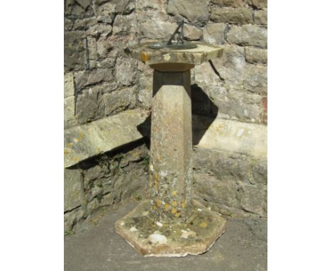 A weathered circular sundial with pierced gnomon set on a hexagonal cast composition stone top, tapered pedestal and base, 92