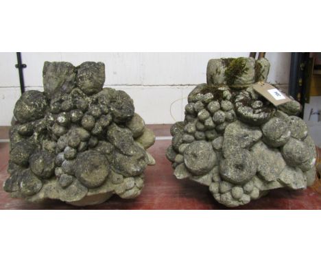 A pair of weathered composition stone finial / caps in the form of fruit-laden cornucopia, each 33 cm high (2)