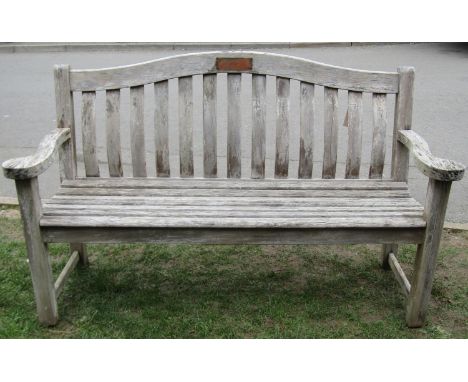 An Alexander Rose weathered/silvered teak three seat garden bench with curved slatted seat and back beneath an arched rail, 1