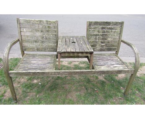 A weathered contemporary companion bench with slatted seat and back and raised central table, 147cm wide (af)