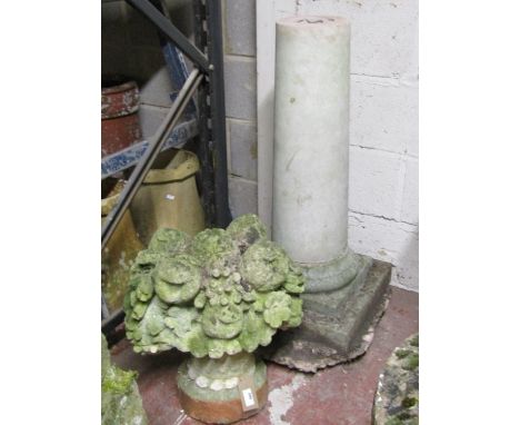 A large weathered composition stone finial in the form of a basket laden with fruits and flowers, raised on a tapering column