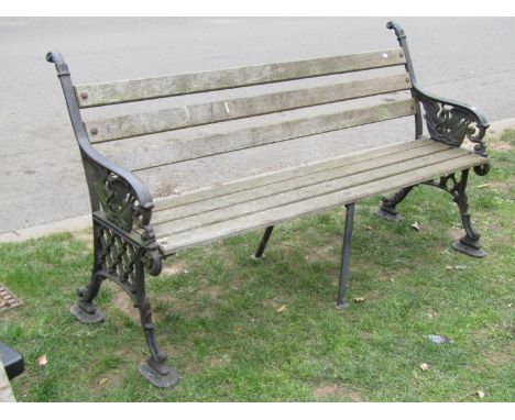 A garden bench with weathered timber lathes, raised on heavy cast iron end supports with eagle, flag and lattice detail, 160c