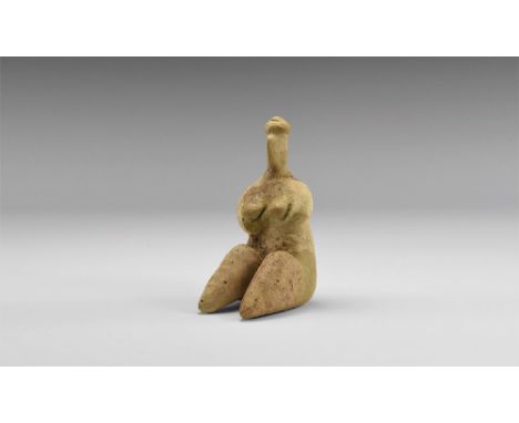 7th-6th millennium BC. A Neolithic ceramic figure of a seated female with small head, prominent nose and bun on top; arms loo