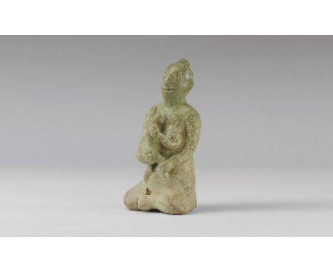 14th-16th century AD. A green-glazed ceramic figurine of a nude seated female, with bun to the back of the head, suckling a b