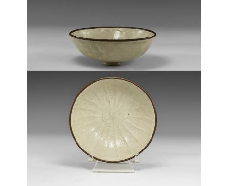 19th century AD. A shallow glazed ceramic bowl with a low foot and low-relief radiating petals to the inner face, each with a