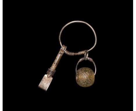 6th-7th century AD. A cosmetic set on a silver ring with the ends twisted round the shank, comprising a green glass bead on a