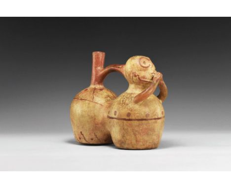 1000-1470 AD. A ceramic double-chambered stirrup vessel with painted red detailing; skeletal head with hands raised to the mo
