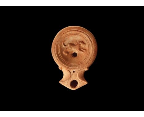 1st-3rd century AD. A ceramic oil lamp with shallow oil dish decorated with a leaping lion; pelta shaped nozzle. 1.7 grams, 9