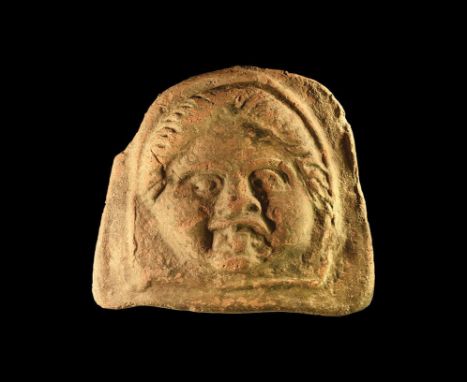 5th-3rd century BC. A ceramic arch-shaped antefix with the face of a Gorgon with hair parted in the centre, large eyes and pr