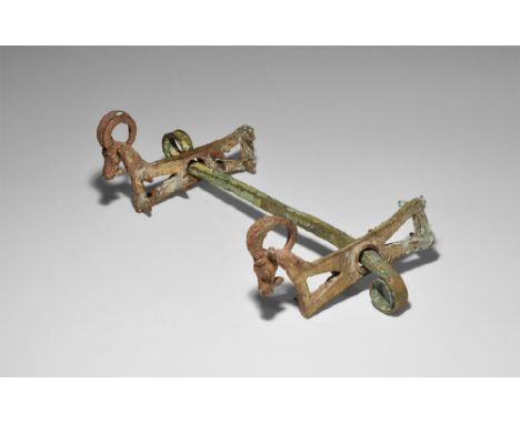 13th-6th century BC. A bronze horse-bit suite comprising: a square-section bar with ends scrolled in opposite directions; two