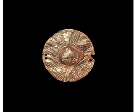 12th-10th century BC. A sheet gold discoid pendant with central dome, radiating blocks of pointillé decoration, pierced in fo
