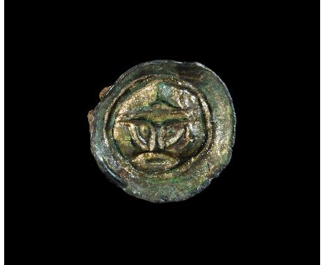 6th century AD. A cast button brooch of Class Bi with stylised helmetted face to the centre, raised border and chamfered rim;